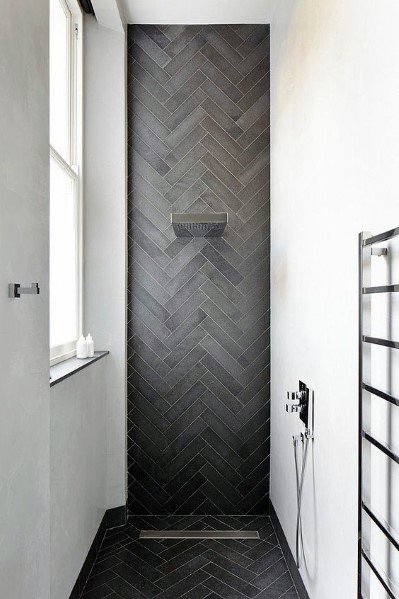 Sleek shower with black herringbone tiles, modern fixtures, and a minimalist design.