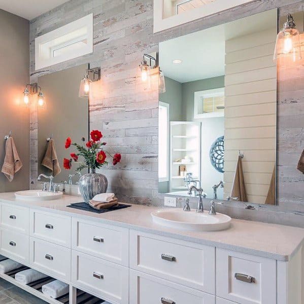 Farmhouse-style bathroom with double vanity, wood accent wall, and glass sconce lighting.