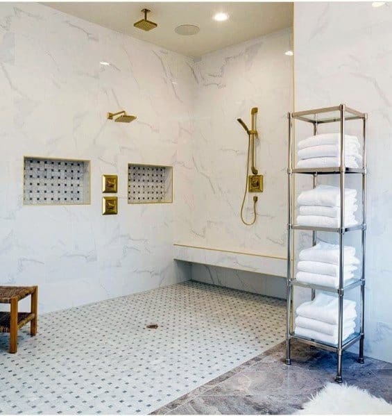 Luxurious bathroom with golden fixtures and a shelf of neatly folded white towels