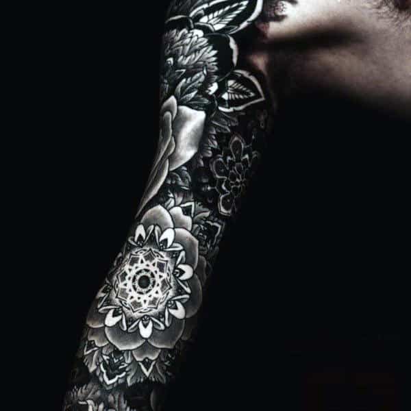 Arm with intricate black and white floral and geometric tattoo sleeve