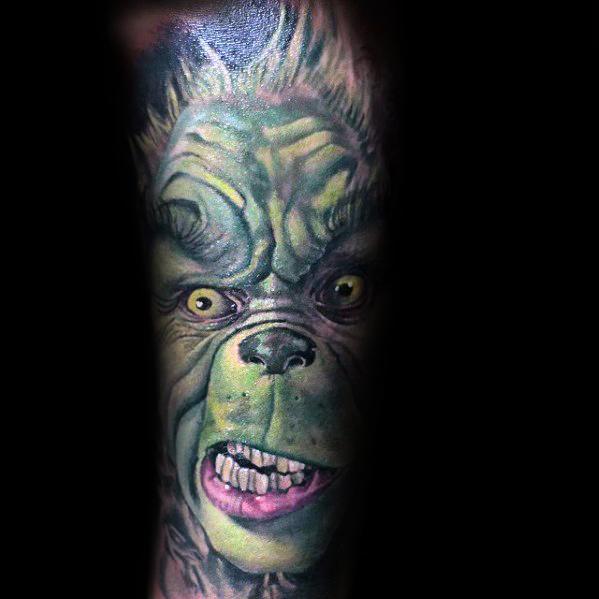 Realistic Christmas tattoo of the Grinch with an intense expression, featuring detailed shading and vibrant green tones for a bold holiday design.
