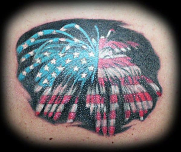Tattoo of a firework explosion designed like the American flag, with red and white stripes on one side and blue with white stars on the other.