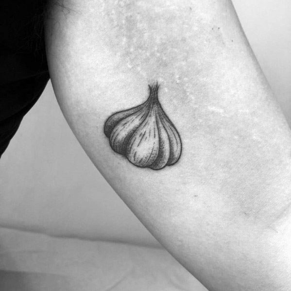 Minimalist black and grey garlic tattoo with fine shading, placed on the arm for a simple yet elegant botanical design.