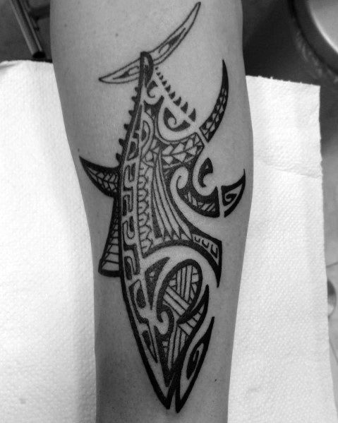 Tribal-style tuna fish tattoo on a man's forearm, featuring intricate Polynesian-inspired patterns and bold black ink for a striking design.