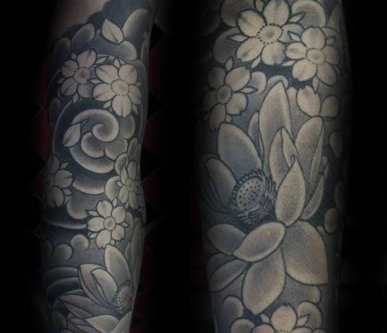 Black and grey Japanese-style sleeve tattoo featuring intricately shaded cherry blossoms, swirling wind patterns, and delicate lotus flowers