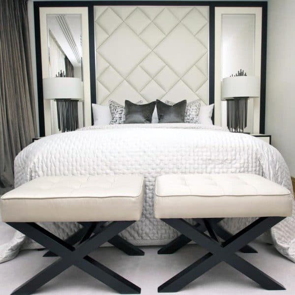 Luxury bedroom with diamond-pattern headboard, white bedding, and two upholstered benches.