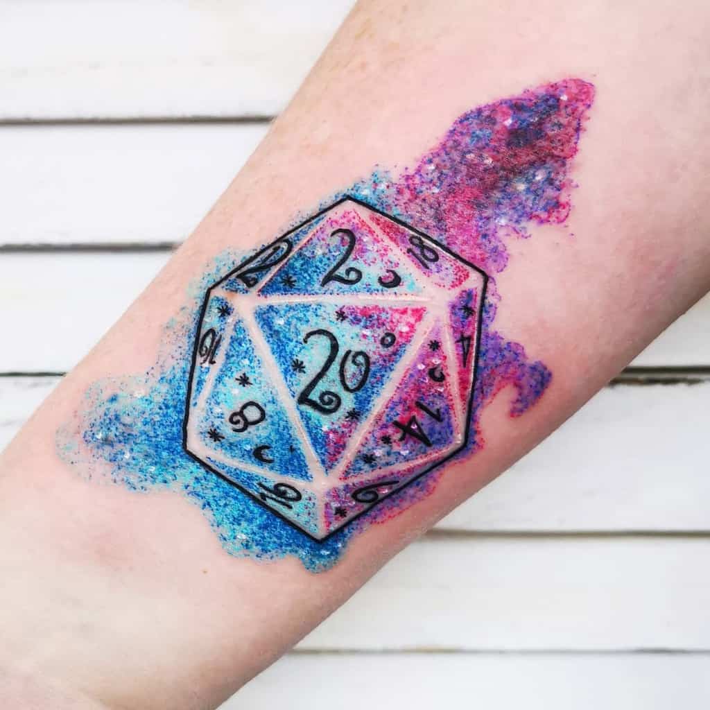 Whimsical D20 dice tattoo with cosmic pink and blue watercolor splashes, accented by starry details for a dreamy fantasy vibe