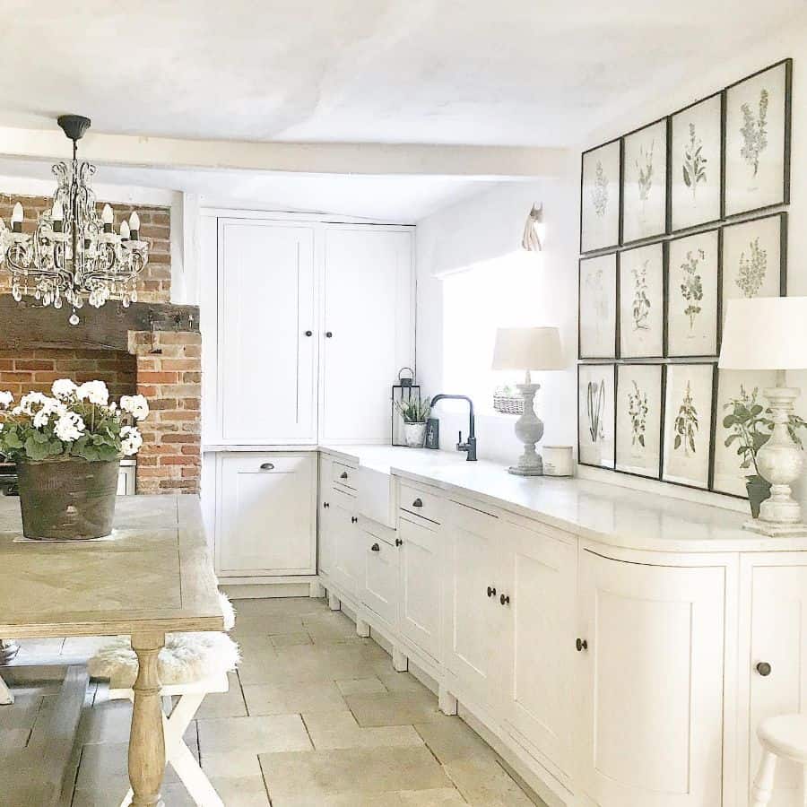 vintage farmhouse kitchen with white cabinets and framed plant wall art