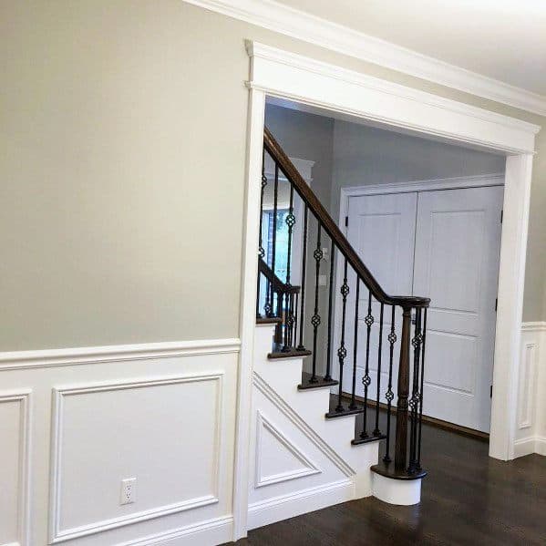 Classic home design with white chair rail molding, dark wood stairs, and wrought iron railings for timeless elegance