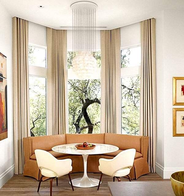 Modern dining nook with floor-length beige curtains, a round table, and a cozy built-in bench.