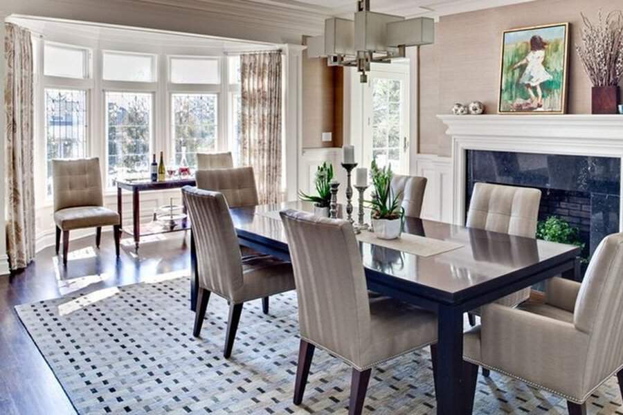 Bright dining room with patterned bay window curtains, a sleek table, and upholstered chairs.