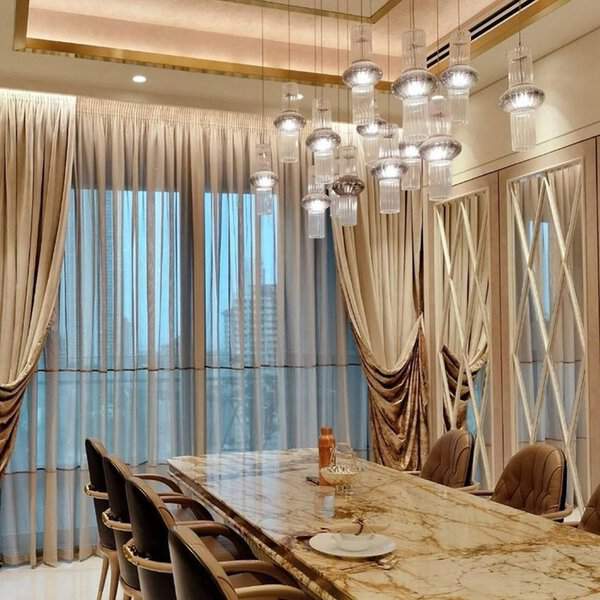 Luxurious dining room with metallic-accented drapes, a marble table, and elegant pendant lighting.