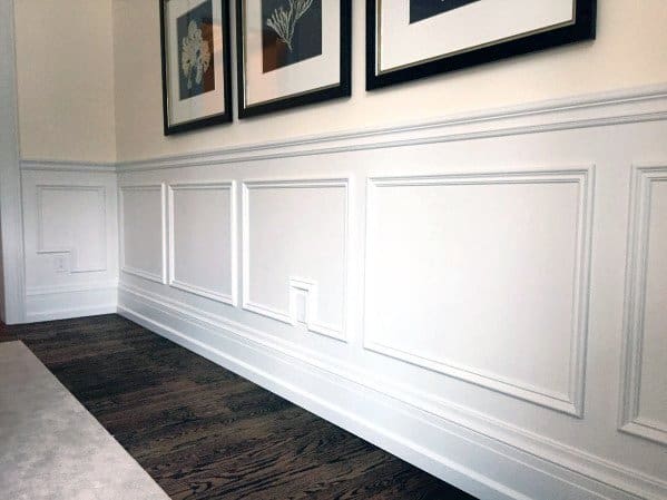 Dining room with white chair rail molding, dark wood flooring, and framed artwork for a refined and elegant look