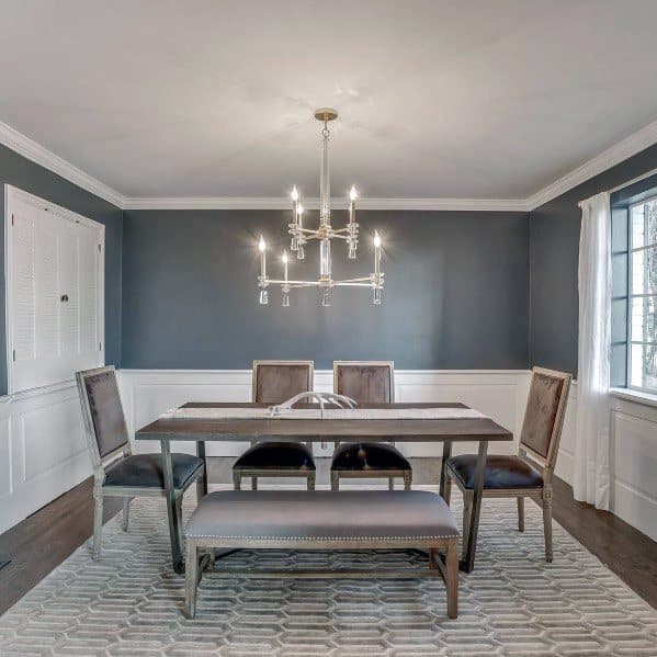 Chic dining room with gray walls, white chair rail molding, elegant chandelier, and modern furniture for a sophisticated style