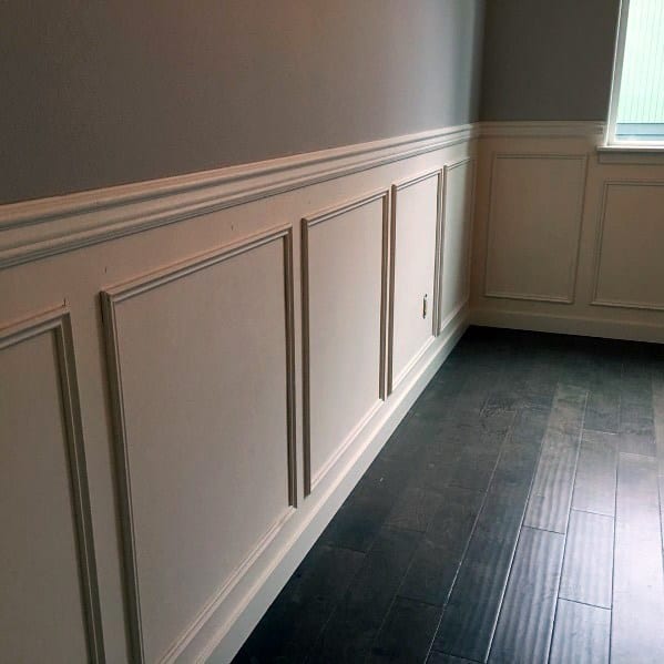 Simple yet elegant room with white chair rail molding, gray walls, and dark wood flooring for a timeless look