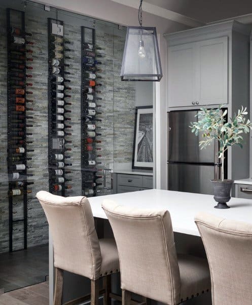 Modern kitchen with a wine rack, white island, beige chairs, stainless steel fridge, and wine-inspired pendant light