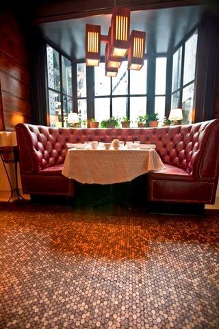 Cozy dining nook with red leather booths, large windows, and penny tile flooring.