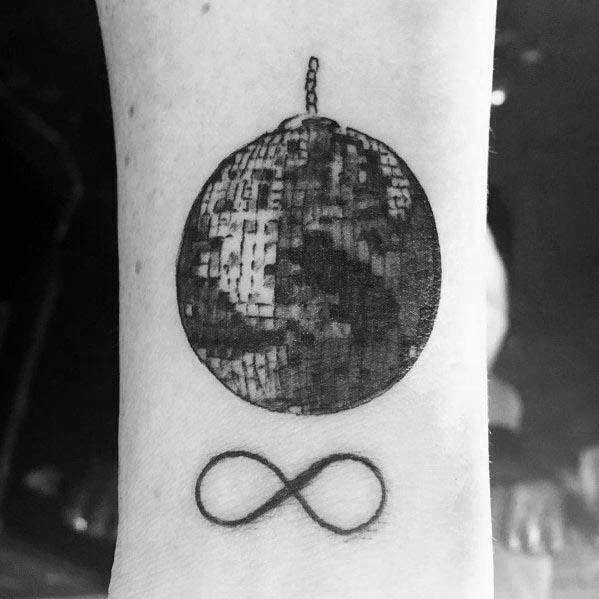 Black ink disco ball tattoo on the wrist with an infinity symbol below, combining a love for music and timeless energy in a minimalist design.