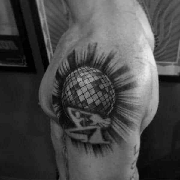 Bold disco ball tattoo on the shoulder with a glowing effect, featuring a figure holding it up, symbolizing strength and passion for music.