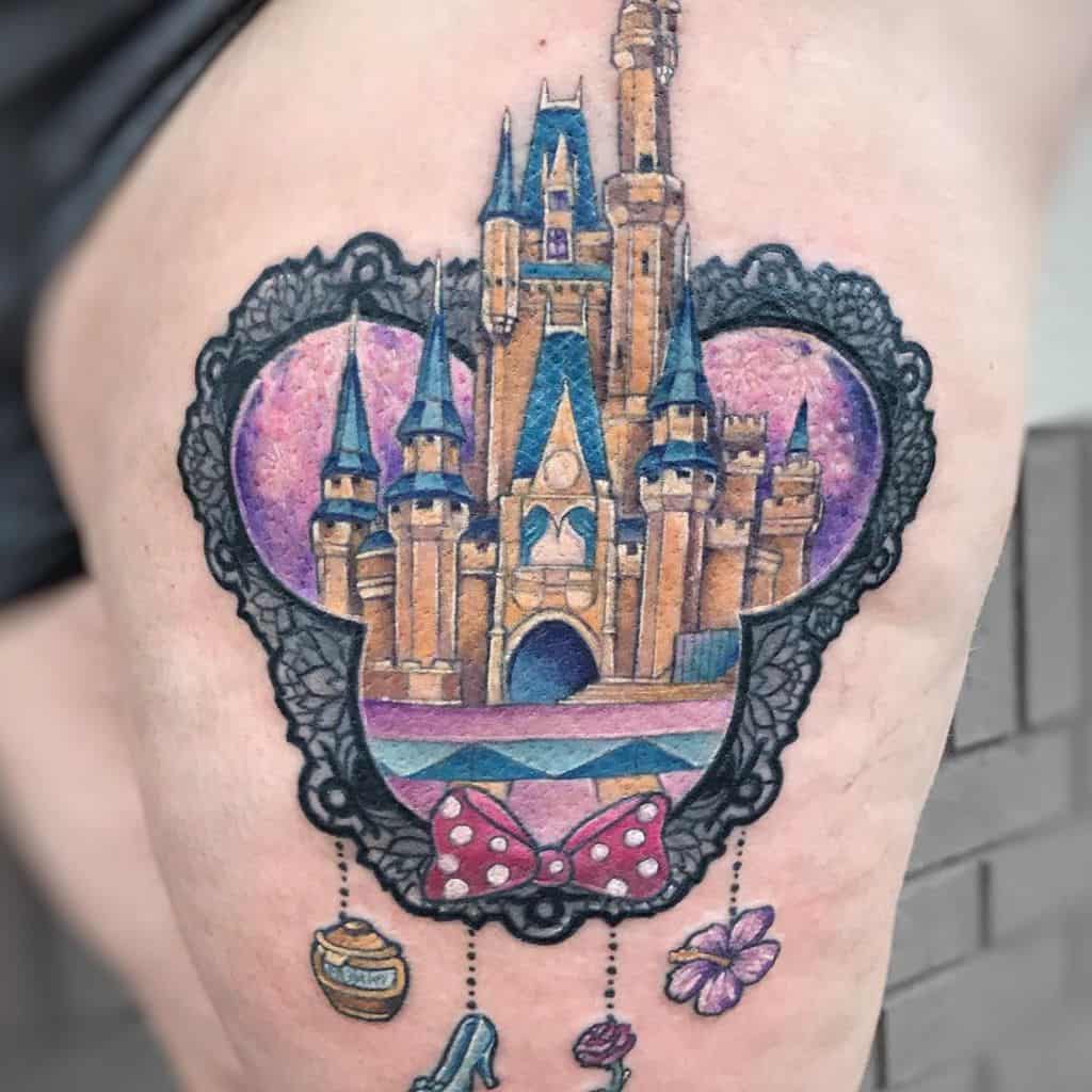 Colorful thigh tattoo featuring a fairytale castle inside a lace-framed Mickey silhouette, with dangling charms and a red polka-dot bow.