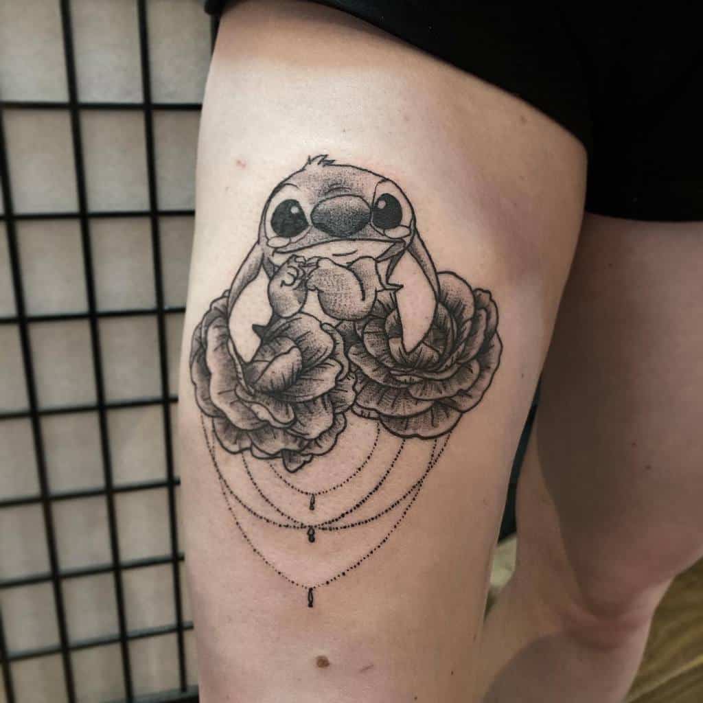 Black and gray tattoo of Stitch from Lilo & Stitch holding a flower surrounded by large roses, with delicate chains of dots, on the thigh.