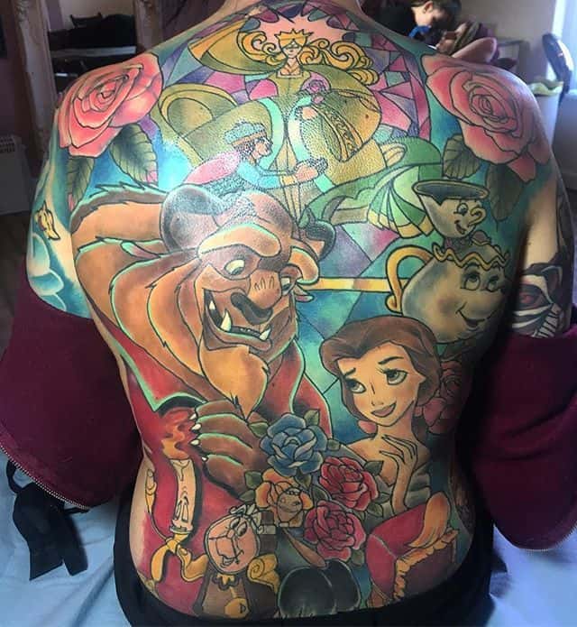Full back tattoo in a stained glass style featuring Belle, the Beast, Mrs. Potts, Chip, and roses, with intricate colors and shading.