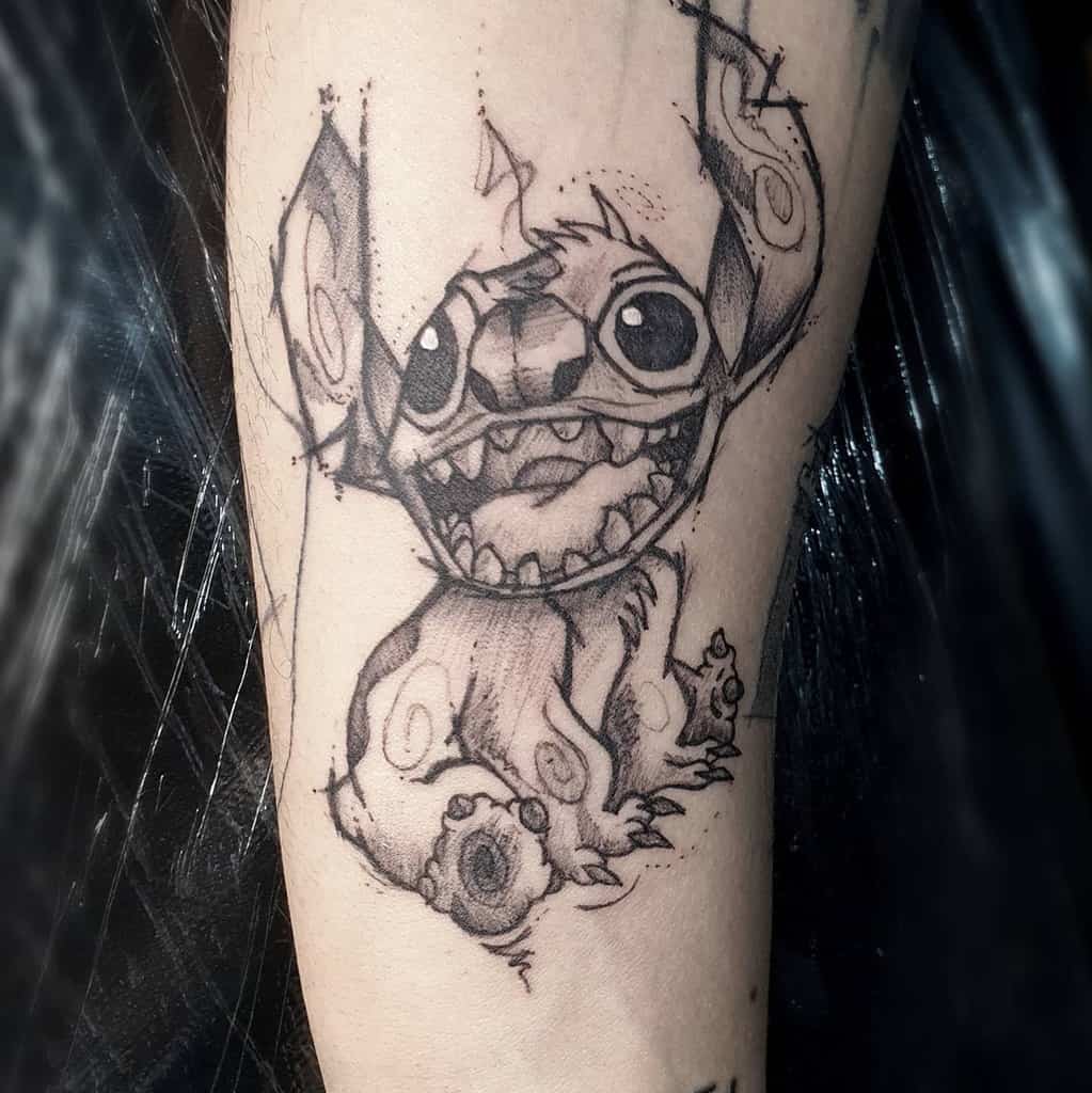 Detailed black and white tattoo of Stitch from Lilo & Stitch with an expressive smile and swirling patterns on his ears.