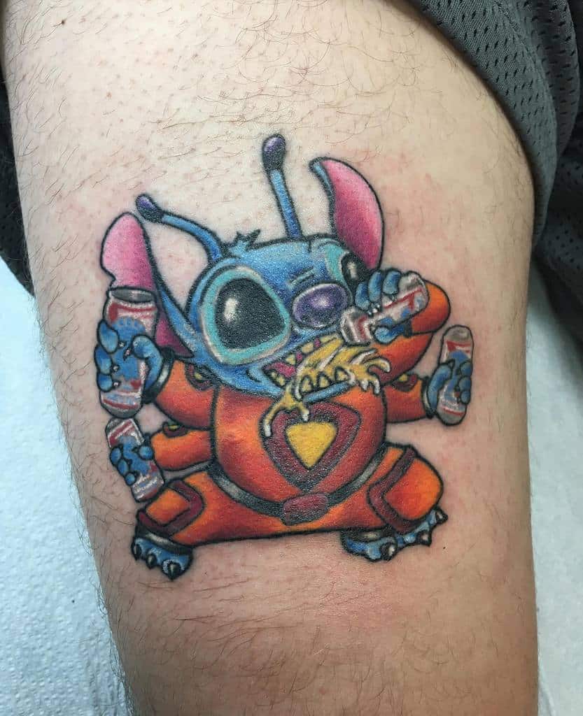 Colorful tattoo of Stitch from Lilo & Stitch wearing an orange suit, holding soda cans and eating noodles, on the upper arm.