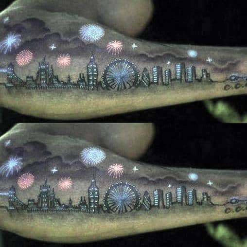 Tattoo of a city skyline at night with fireworks bursting above, featuring landmarks like Big Ben and the London Eye in a detailed, glowing design.