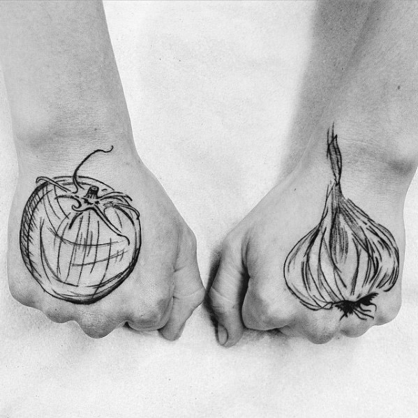 Sketch-style tomato and garlic tattoos on hands, featuring bold lines and artistic shading for a raw and expressive design.