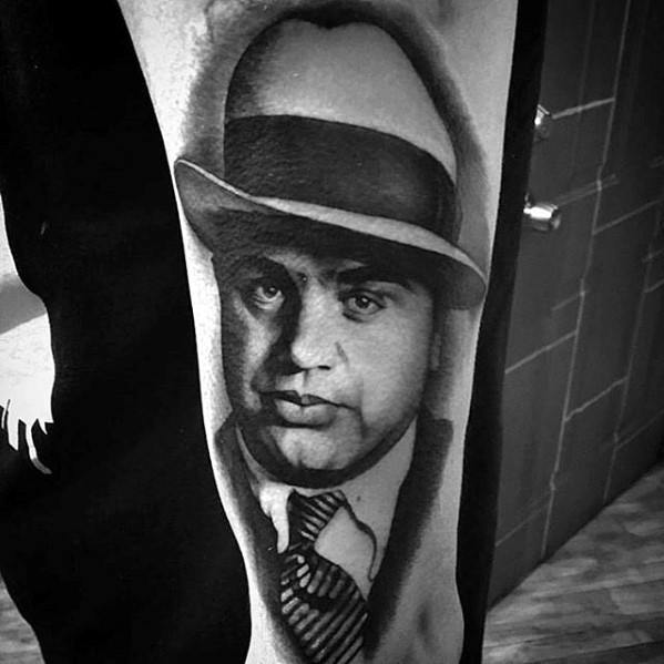 Al Capone tattoo featuring a black-and-white portrait of the gangster, wearing his iconic fedora and a serious expression.