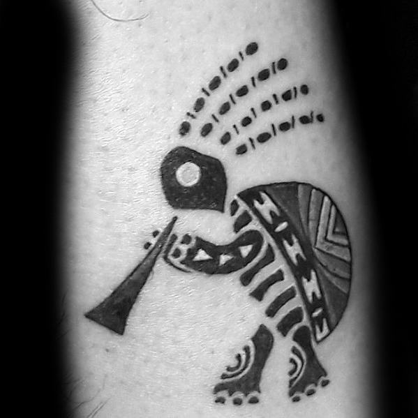 Creative Kokopelli tattoo with a turtle shell design and tribal patterns, featuring dotted hair and a bold flute detail.