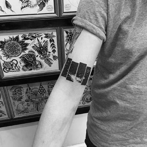 Distressed Black Flag bars tattooed on the forearm with a cracked, worn effect, symbolizing raw energy and rebellious wear.