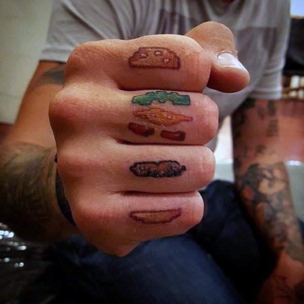 Tattoo of pixelated cheeseburger layers on fingers, featuring buns, lettuce, cheese, and meat