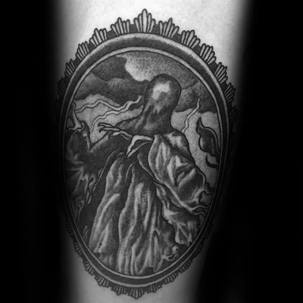 Black and grey tattoo of a Dementor framed in an ornate oval, with dramatic shading and eerie clouds swirling in the background.