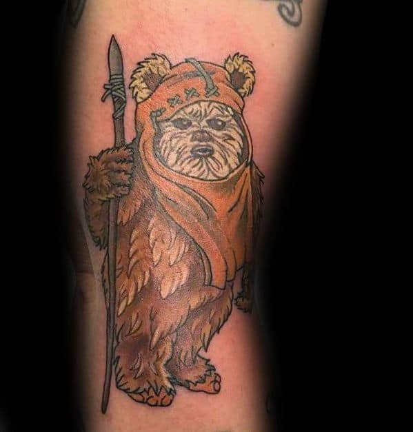 Classic Ewok tattoo in muted tones, holding a spear and wearing an orange hood with a serious expression.