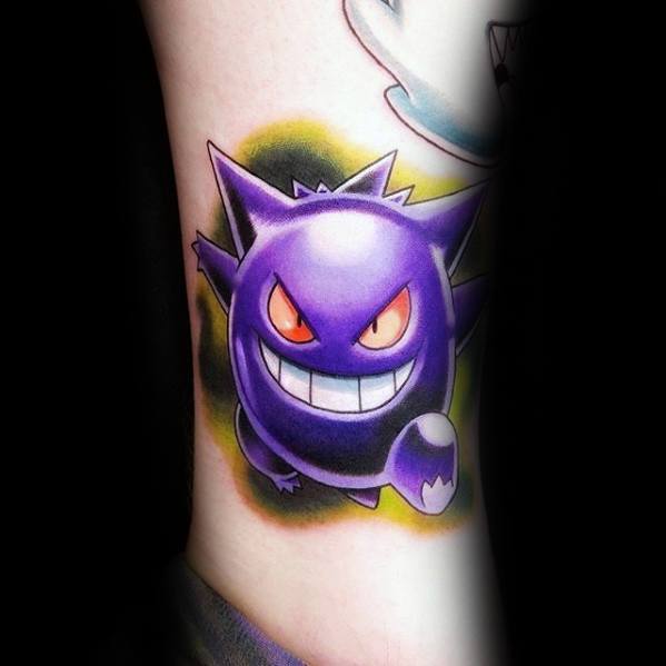 Bright and bold Gengar tattoo with glowing red eyes, a wide grin, and a vivid green-yellow aura behind the playful ghost figure.