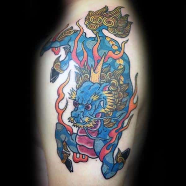Colorful Kirin tattoo with blue body, golden mane, and red flames, depicted in a bold, energetic pose on the upper arm.