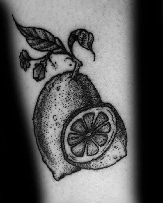 Blackwork tattoo of a whole lemon with a sliced half, leaves, and a small flower, shaded using dotwork technique.