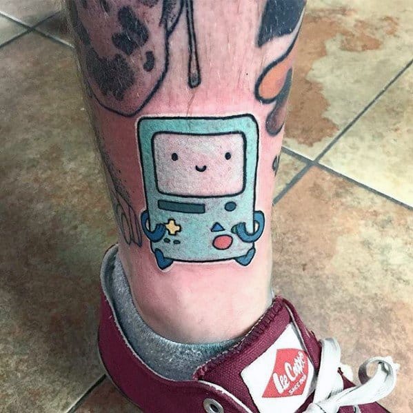 Cute Adventure Time tattoo of BMO with a happy expression, inked on the lower leg above the ankle.