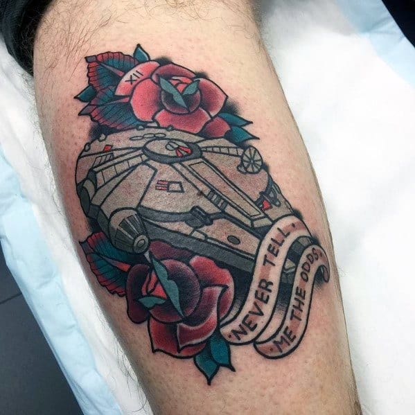 Millennium Falcon tattoo surrounded by red roses and a banner reading “Never tell me the odds” in bold lettering.