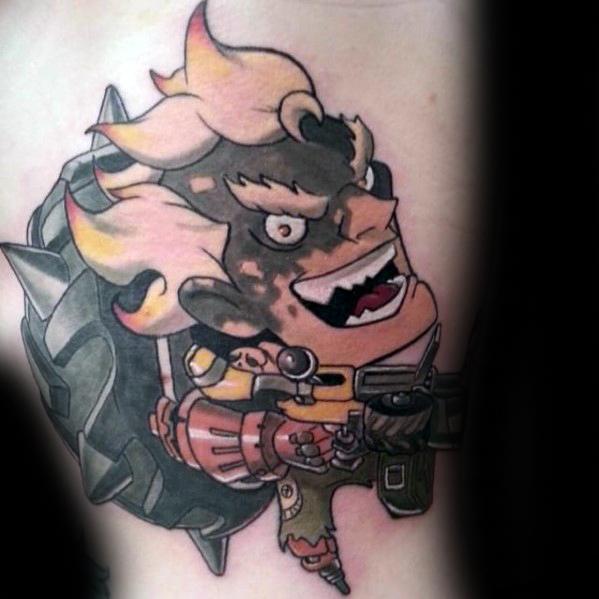 Cartoon-style tattoo of Junkrat from Overwatch with his signature wild grin and explosive gear inked in bold colors.