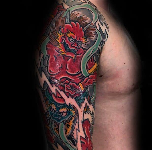 Vibrant Raijin upper arm tattoo with bold red skin, lightning bolts, and swirling elements in traditional Japanese style.