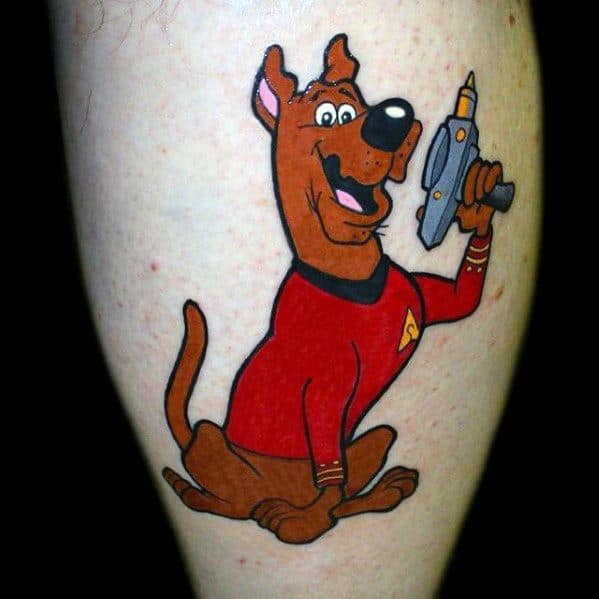 Tattoo of Scooby-Doo dressed as a Star Trek officer in a red uniform, holding a futuristic blaster with a cheerful expression.