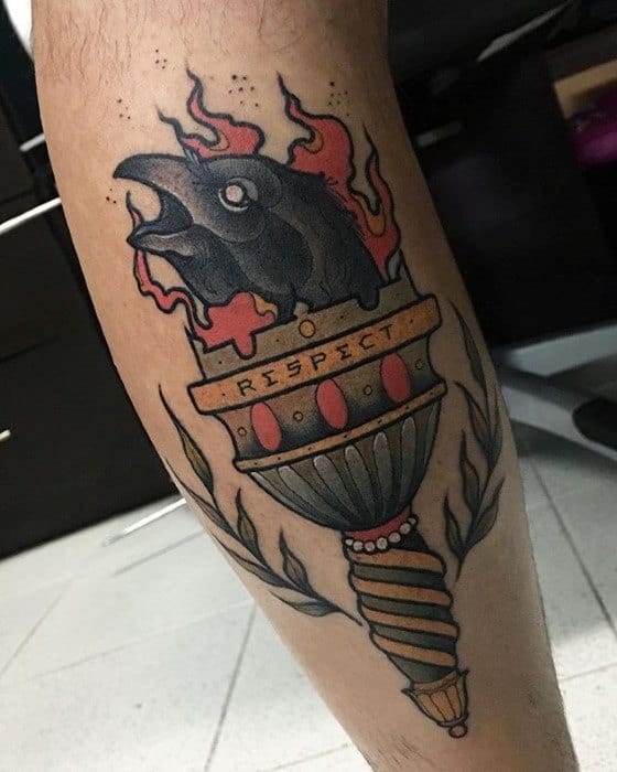 Torch tattoo on calf featuring a black raven head in flames, with a “RESPECT” banner and ornamental handle details.
