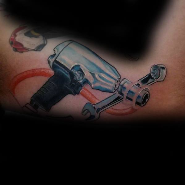 Tattoo of a chrome impact wrench with a socket and spanner, featuring red cable accents in a realistic, detailed style.