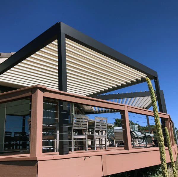 Sleek pergola with black metal frame, slatted roof, and outdoor dining area on a raised deck.