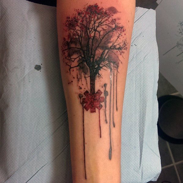 Forearm tattoo featuring a tree growing from the Red Hot Chili Peppers logo, with dripping ink effects and red accents for an artistic look.