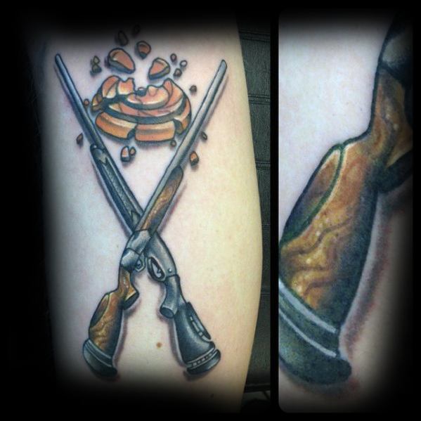 Crossed double-barrel shotgun tattoo with detailed woodgrain handles, featuring a shattered clay target above for a dynamic hunting theme.