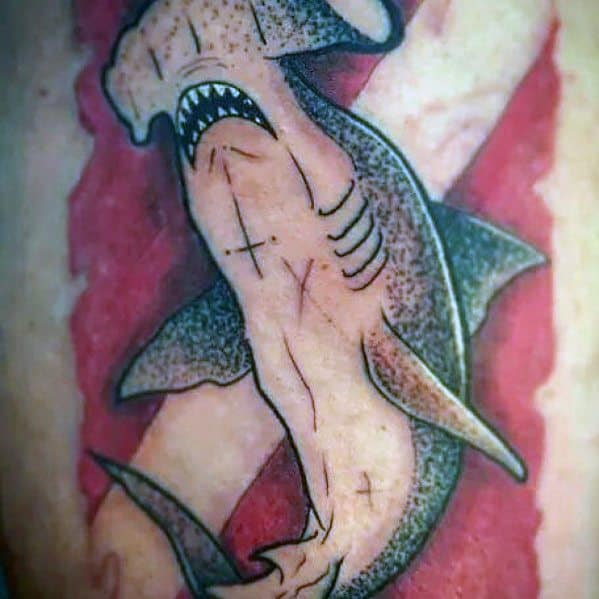 Tattoo of a shark with its underside resembling a human torso, set against a red and white dive flag background, symbolizing marine adventure.